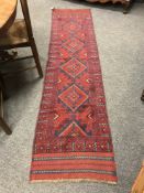 A Persian Meshwani carpet runner on red ground, 64 cm x 258 cm.