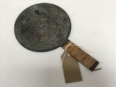 An early twentieth century Japanese hand mirror with embossed decoration, width 14 cm.