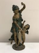 A patinated bronzed sculpture depicting a maiden with winged angel, standing on circular plinth,