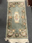 A fringed Chinese rug on green ground, 76 cm x 155 cm.