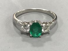 A platinum emerald and two stone diamond ring, size O, the total diamond weight approximately 0.5ct.