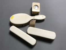 Three antique ivory dressing table brushes together with a miniature dressing table clock.