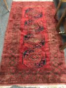 A fringed Afghan rug on red ground