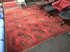 A fringed Afghan carpet on red ground