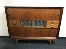 A mid 20th century teak multi drawer sideboard, with sliding panel doors,