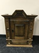 An antique style oak wall cabinet fitted with a drawer,