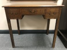 A George III oak side table fitted with three drawers on square legs, width 84 cm.