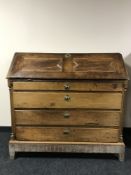 An early 19th century oak bureau with brass key escutcheons, on square tapered legs,