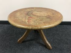 A circular oak pedestal table with a tooled leather top depicting a dragon