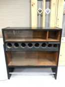 A mid 20th century cocktail cabinet, with glass sliding doors and graduated wine bottle holders,