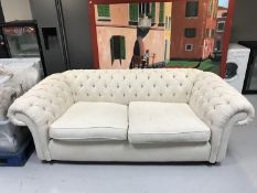 A three seater Chesterfield style settee upholstered in cream button fabric