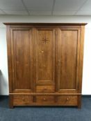 A pine triple door wardrobe fitted four drawers