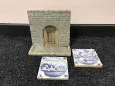 A tray of two Delft blue and white tiles and a miniature fireplace