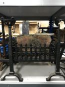 A cast iron fire grate with fire dogs and a cast metal stand and hearth brush