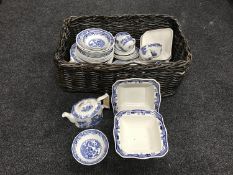 A wicker log basket containing Masons blue and white dinner ware
