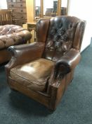 A brown button leather wing chair