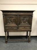 An early 20th century carved oak double door cabinet on barley twist stand, width 116 cm.