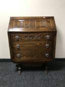 A carved oak bureau with metal handles