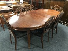 A circular mahogany dining table on reeded legs with three leaves and six shield back dining chairs