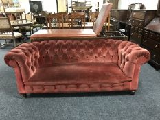 A late Victorian button backed Chesterfield settee raised on ceramic castors