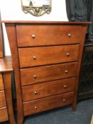 A contemporary stained pine five drawer chest