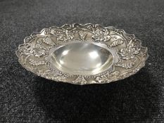 A white metal scalloped edge bowl with grape decoration