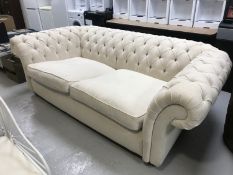 A three seater Chesterfield style settee upholstered in cream button fabric