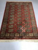 A red fringed woollen rug and a pink floral patterned rug