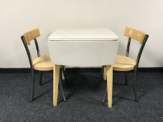 A mid twentieth century drop leaf kitchen table together with two chairs