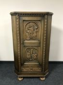 A carved oak corner cabinet on bun feet