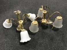 Two brass three-way light fittings with glass shades