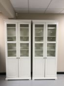 A pair of white Ikea glazed door bookcases