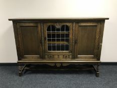 A continental oak triple door sideboard with glass panel door