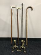 A pair of brass fire dogs together with a white metal mounted walking stick with bone handle,