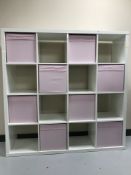 A set of white Ikea cube shelves and eight pink storage baskets