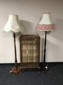 A walnut single door display cabinet and two standard lamps