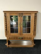 A Continental oak hanging cabinet with stained glass doors