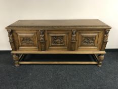 An early 20th century heavily carved oak triple door sideboard