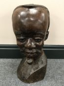 A carved hardwood head of an African man smoking a pipe