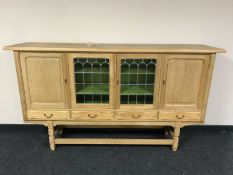 A blond oak four door sideboard with leaded glass panel doors
