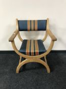 A blond oak X-frame carver armchair upholstered in a blue striped fabric