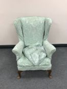 A mid-20th century Parker Knoll wingback armchair with a green loose cover