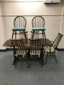 An Ercol refectory dining table together with five rail-back chairs (one carver and four singles)