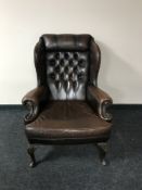 A brown button Chesterfield wing back armchair