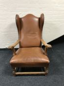An early 20th century oak framed tan leather wingback armchair