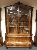 An 18th century Dutch marquetry display cabinet on bombe three drawer chest base,