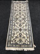 A fringed woollen floral patterned runner on cream ground