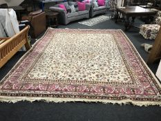 A large floral fringed carpet on cream ground