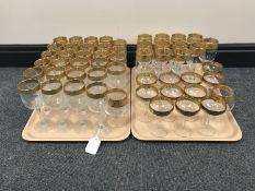 Two trays containing a suite of gilt-rimmed glassware