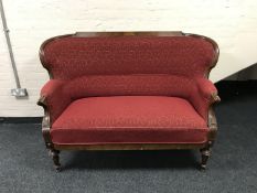 An antique carved mahogany framed settee upholstered in red fabric